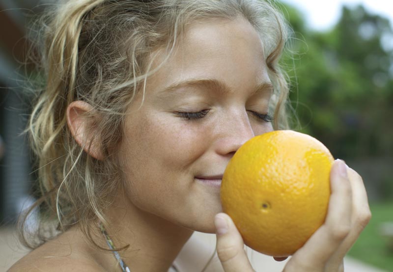 Kvinna som luktar på en apelsin.