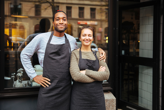 Två glada kollegor poserar utanför ett café